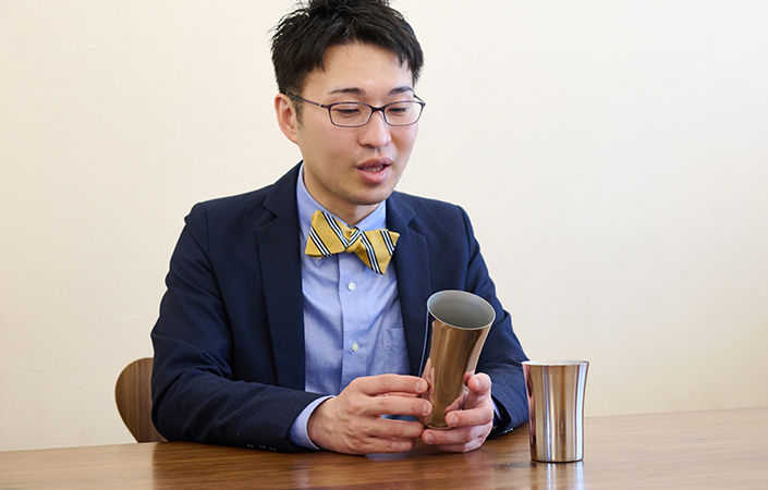 ステンレスのタンブラーをみるショーヘイさん