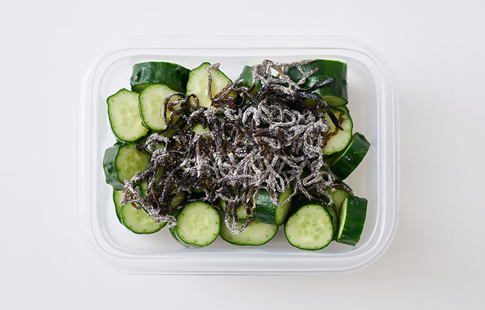 きゅうりと塩昆布をコンテナーに入れ、ごま油を加えます。