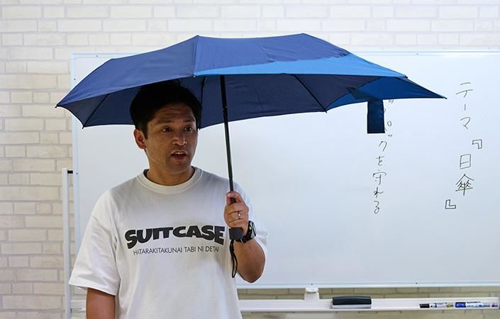 バックパックを守れる傘の余白を見せる佐藤バイヤー