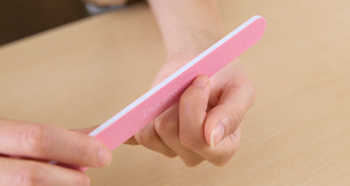 爪の左右どちらか（先端）に 爪やすりを当てている様子