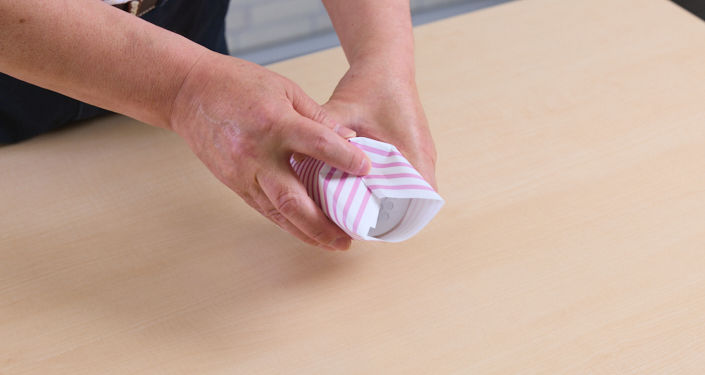 箱に巻きつけた包装紙の下部分から中央に向かって、等間隔にタックを折ります。